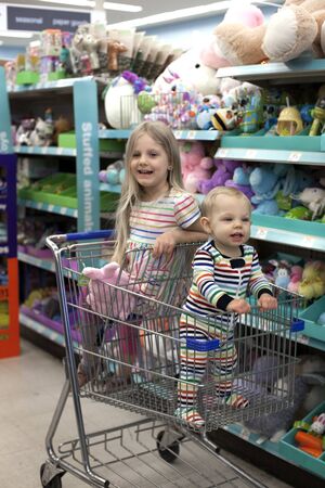 Eau Claire, WI, USA - October 20, 2019: Walgreens. Little girl and baby boy sitting in shopping cart at toy aisleのeditorial素材