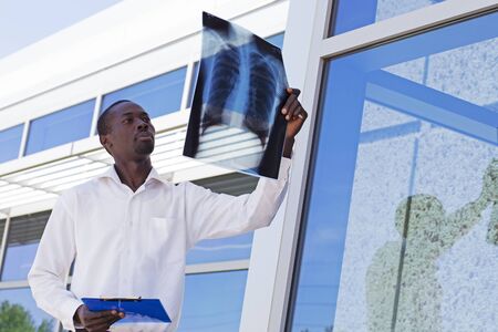 Portrait of young doctor holding x-ray of chest. Radiologist examining fluorography x-ray outdoors. Pneumonia, corona virus conceptの写真素材