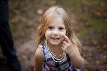 Portrait of smiling little girl walking outdoors. Child wearing dress and necklaces. Childhood conceptの写真素材
