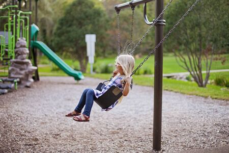 Happy little girl having fun on playground. Child riding a swing. Childhood conceptの写真素材