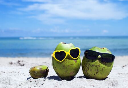 Green coconuts with sunglasses on the beachの写真素材