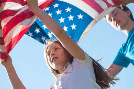 Conceptual photo of cheerful children holding American flag on 4th of July next the house. Independence day.の写真素材