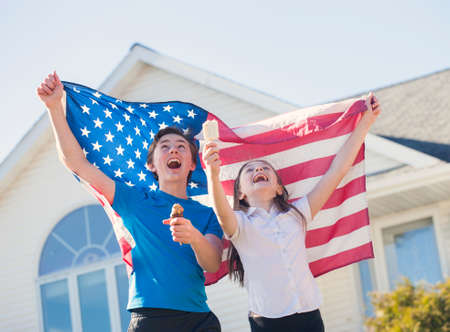 Happy children with American flag running during 4th of July. Independence day.の写真素材
