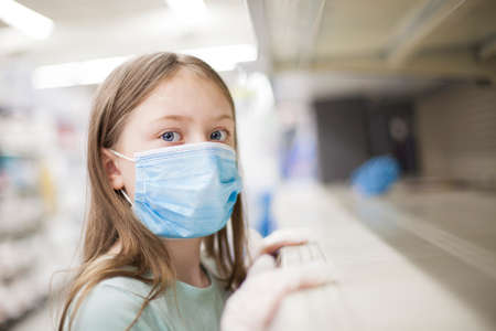 Unhealthy girl in medical mask looking or choosing medicine in pharmacy during pandemic corona virusの写真素材