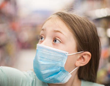 Unhealthy girl in medical mask looking or choosing medicine in pharmacy during pandemic corona virusの写真素材