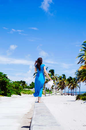 Rear view of happy woman with hat walking on the islandの写真素材