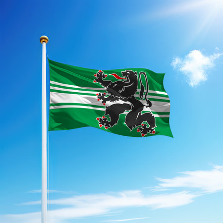 Waving flag of East Flanders is a province of Belgium on flagpole with sky background.の写真素材