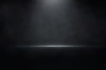 Black stage illuminated by single spotlight with smoky texture and reflective floor