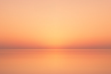 Warm glowing sunset casting orange tones across smooth water, soft horizon viewのイラスト素材