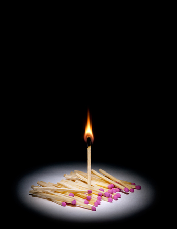 A lot of matches on a black background art  A match is lit 