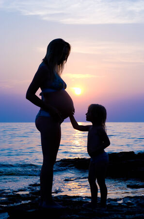 The pregnant woman and the small child  against the sea  の写真素材