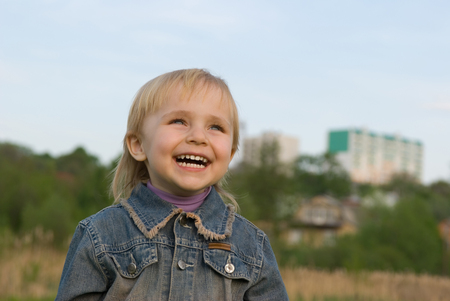 The little girl laughs at a green lawn の写真素材
