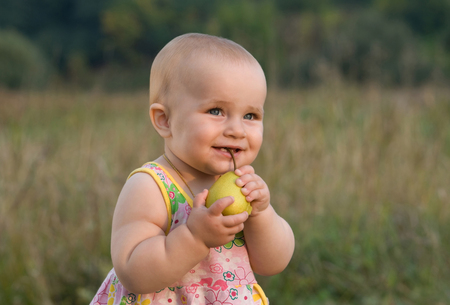 portrait of a cute baby biting fruitの写真素材