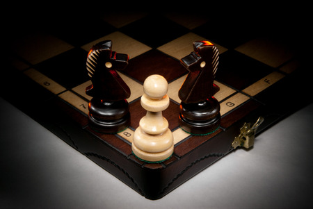 Chessmen on a chess board. A dark background and art illumination.の写真素材