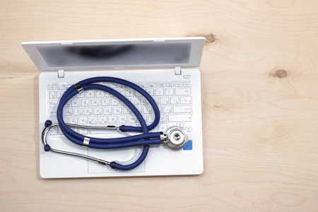 White open laptop with a stethoscope on the wooden table