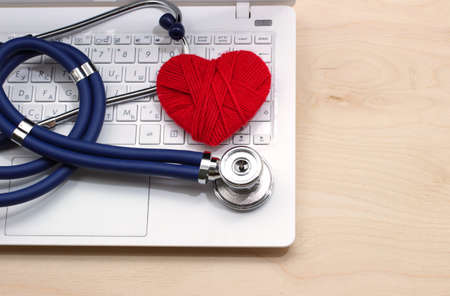 White open laptop with a stethoscope on the wooden tableの写真素材