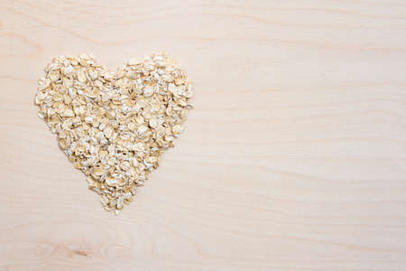 oat flakes in a heart shape on a wooden backgroundの写真素材