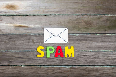 white paper envelope and the word spam on a wooden backgroundの写真素材