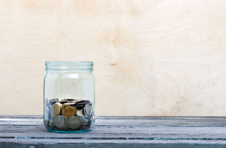 Financial concept. Coins in glass money jar. Wooden backgroundの写真素材