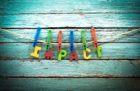 word impact fasten clothespins on a rope behind a wooden backgroundの写真素材