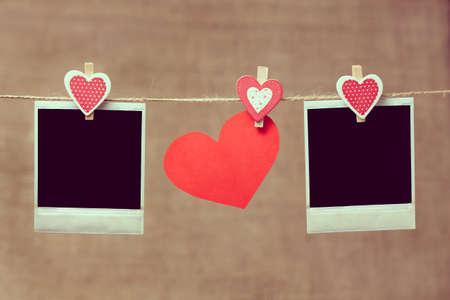 Two polaroid photo frames and heart for valentines day hanging on vintage background with vintageの写真素材