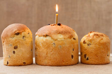 Baked traditional religious easter cake also called kulich with burning candle on vintage textile...