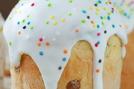 Homemade sweet bread traditional easter cake panettone also called kulich glazed with icing and raisins on vintage textile background. Closeup shotの写真素材