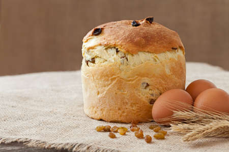 Tasty backed traditional russian kulich easter cake with raisins and eggs on vintage textile...
