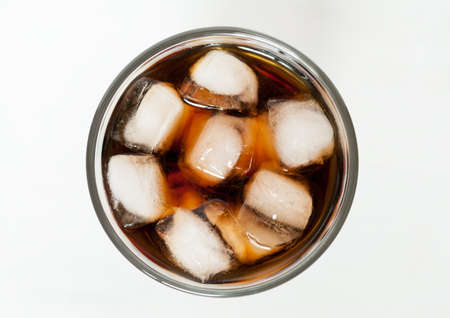 Glass of refreshing cold cola sweet soda drink with bubbles and ice cubes. Top view