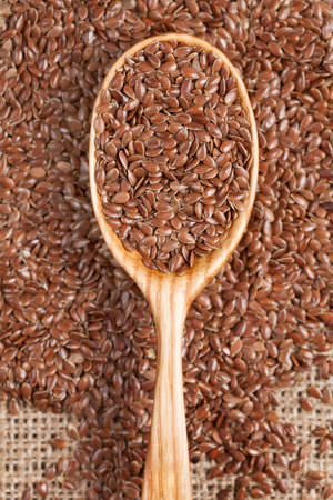 Healthy little brown flax seeds super foods. Flax grain scattered on vintage textiles.の写真素材