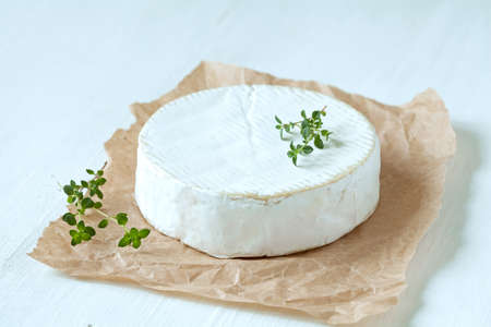 Camembert cheese organic traditional french gourmet food with thyme on parchment. Rustic style, natural light.の写真素材