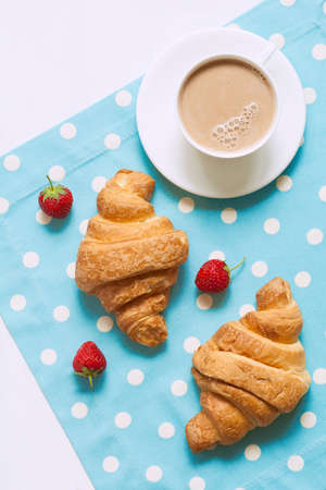 Croissant traditional viennoiserie pastry dessert with a cup of coffe and fresh strawberry on provence style background. Natural light, vivid colors and rustic style.の写真素材