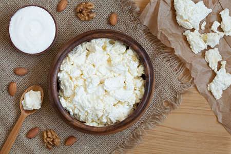 Cottage cheese healthy protein breakfast with sour cream and almond nuts in rustic wooden dish on...