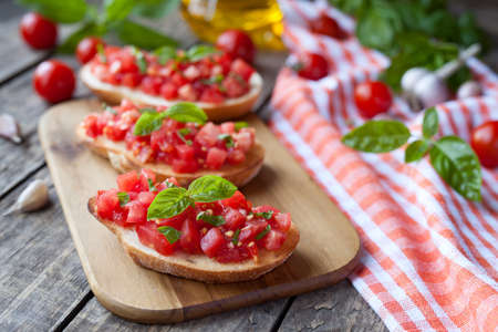 Traditional italian bruschetta vegetarian bread snack antipasti. Roasted sandwich with tomatoes, garlic and basil. Natural light and rustic style.の写真素材
