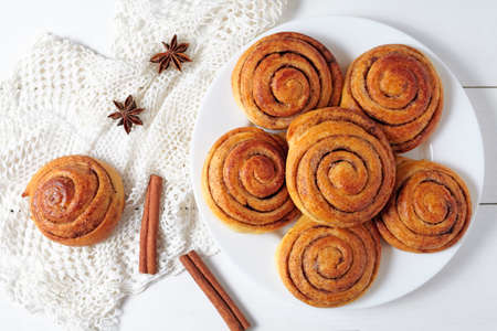 Cinnamon bun rolls christmas sweet dessert on white vintage table. Traditional swedish kanelbullar baked pastryの写真素材