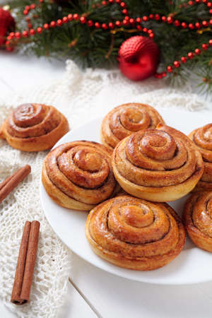 Cinnamon bun rolls christmas sweet dessert on white vintage table with new year decorations. Traditional swedish kanelbullar baked pastryの写真素材