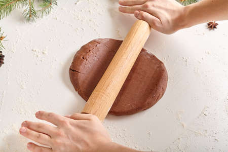 Gingerbread cookies preparation recipe, unrecognizable woman hands making dough with rolling pin on white kitchen table. Traditional homemade christmas dessertの写真素材