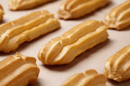 Eclairs traditional French profiterole recipe with whipped cream on baking sheet background. Close...
