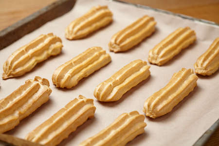 French traditional eclairs or profiterole dessert with whipped cream on baking sheet backgroundの写真素材