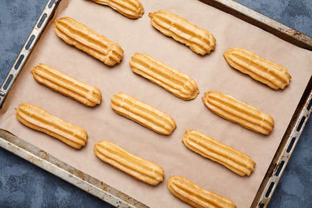 Eclairs or profiterole traditional French cuisine recipe with whipped cream on baking sheet backgroundの写真素材