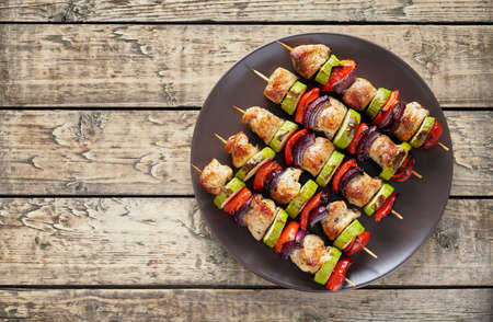 Turkey or chicken shish kebab skewers with pepper tomatoes and onion on rustic wooden table backgroundの写真素材