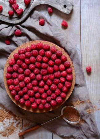 Homemade delicious chocolate cake cheesecake with fresh raspberries on the rustic wooden table. Horizontal top view.の写真素材