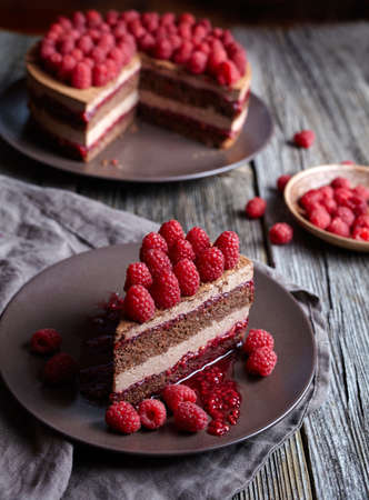 Homemade chocolate mousse cake cheesecake with fresh raspberries on the rustic wooden table. Concept of a romantic breakfast. Souffle dessert.の写真素材