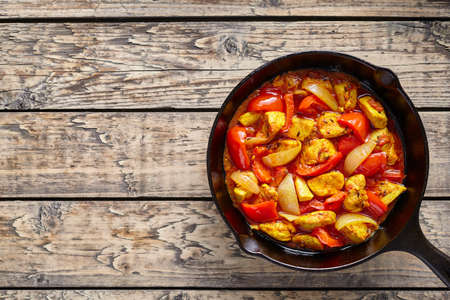 Chicken jalfrezi dietetic traditional Indian culture curry spicy fried meat with vegetables asian food in cast iron pan on vintage table backgroundの写真素材
