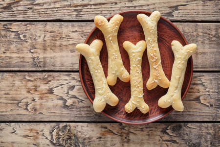 Creative traditional Halloween dough bones cookies vegetarian snack mozzarella on rustic wooden table. Food decorations for holiday celebration party.の写真素材
