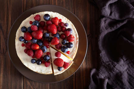 Delicious Homemade creamy mascarpone New York Cheesecake. Top viev. Cheese cake with berries on dark wooden table. Cream mousse dessert.の写真素材