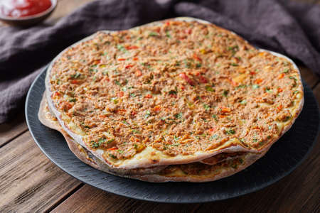 Lahmacun turkish delicious pizza with minced beef or lamb meat, paprika, tomatoes, cumin spice, parsley baked spicy middle eastern arabian food on rustic wooden table backgroundの写真素材