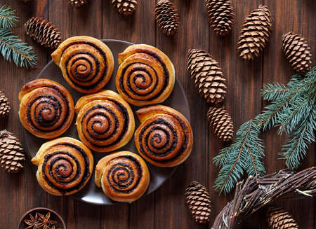 Sweet Homemade christmas baking. Cinnamon rolls buns with cocoa filling. Kanelbulle swedish dessert. Festive decoration with pine cones and Christmas treeの写真素材