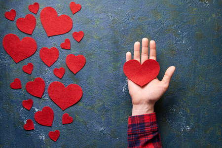 Woman hand holding red wool heart. Valentines Day concept. Symbol of love. Flat lay. Top view table....