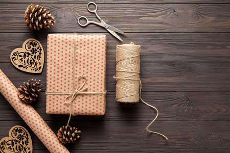 Wrapping gifts in rustic style on birthday, Mothers Day, Christmas or holidays. Dark wooden background. Flat lay. View from above.の写真素材